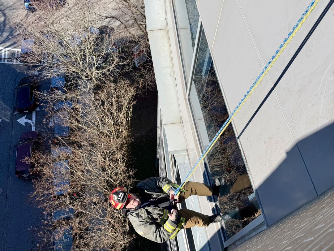 Capt. Champion rappels down the building while waving at children inside CHOA Scottish Rite. 