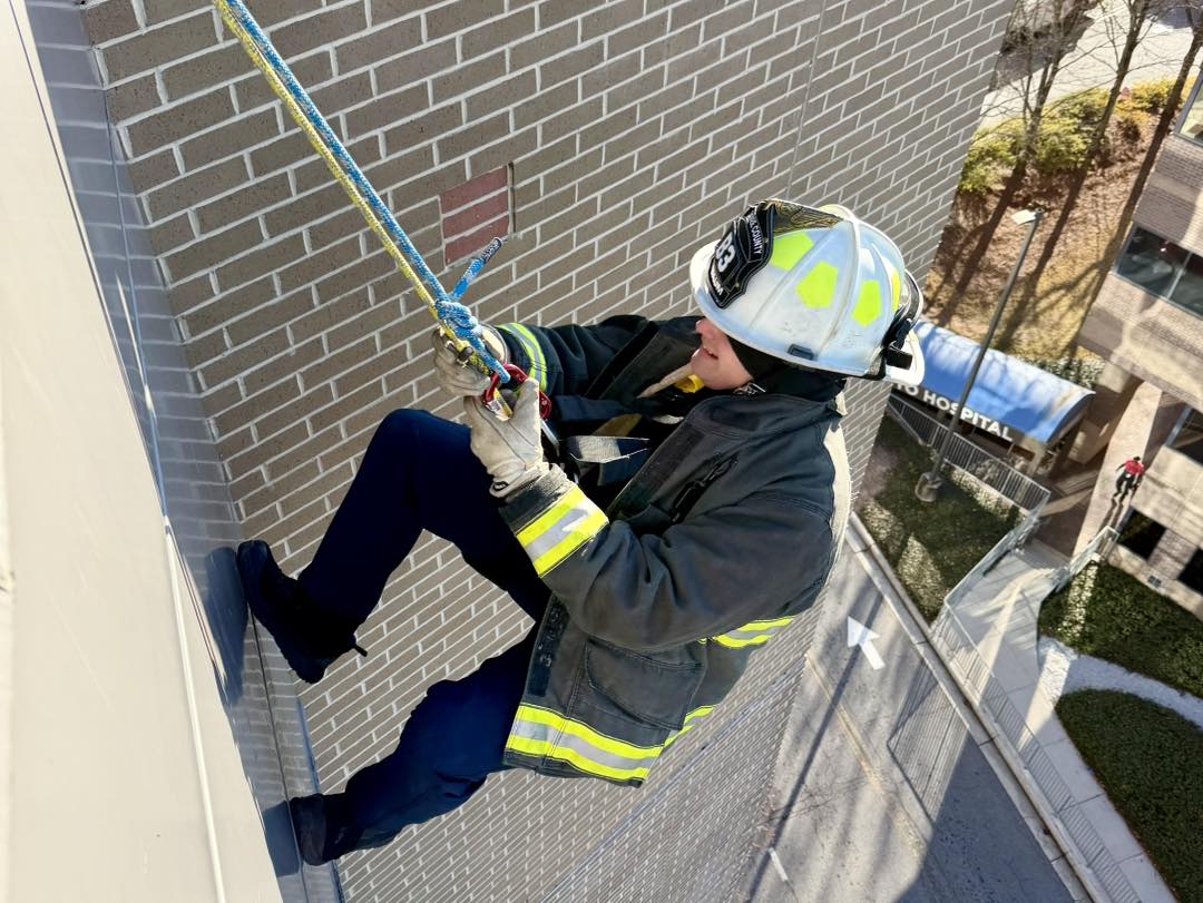 Chief Baum rappels down the building while waving at children inside CHOA Scottish Rite.  